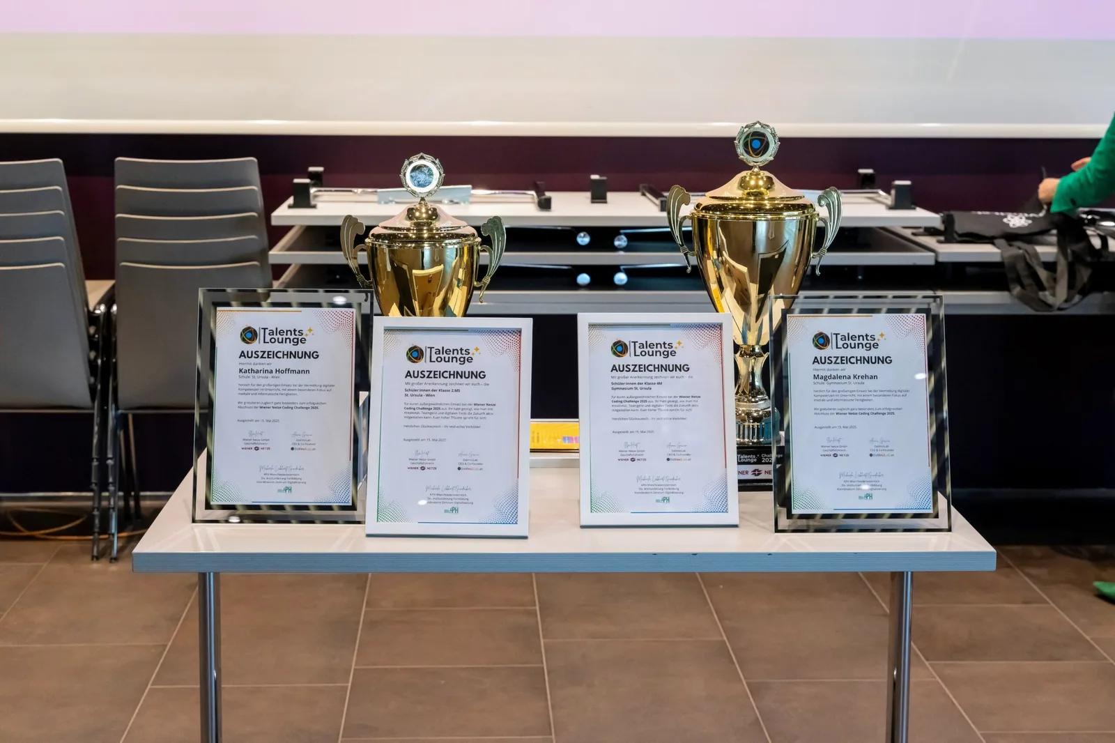 Pokale und gerahmte Auszeichnungsurkunden der TalentsLounge auf einem Tisch